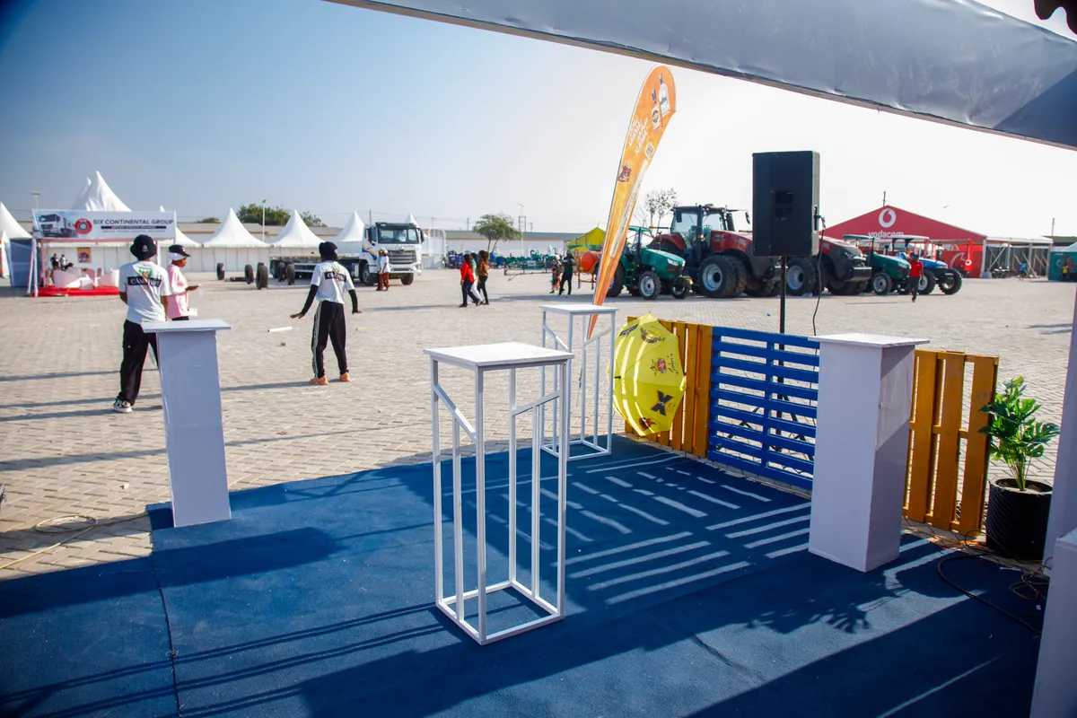 Wide view of Nane Nane Grounds, Dodoma, with tractors and agribusiness exhibitors surrounding the JBL activation corner