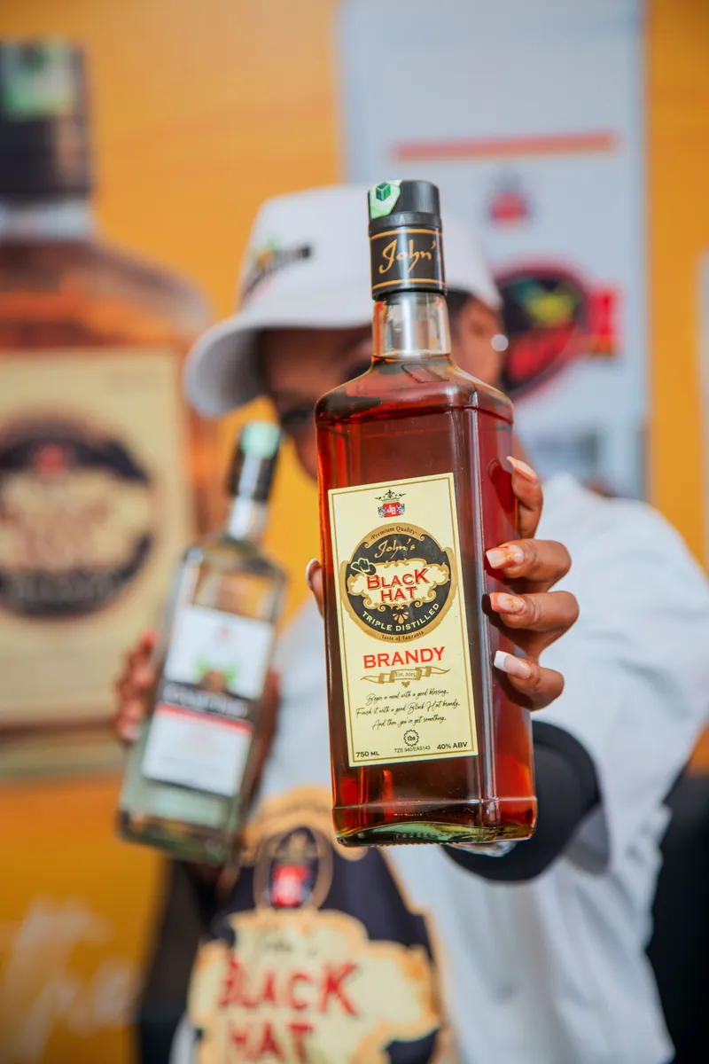 Close-up of a Black Hat Brandy bottle held by a JBL brand ambassador during product sampling
